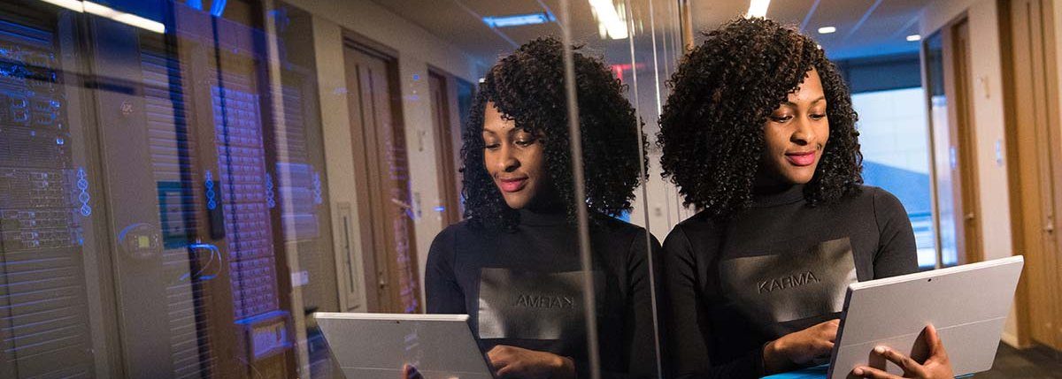 Women standing with a laptop near a server room.