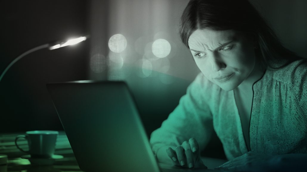 A woman examines her laptop screen with a discerning eye, embodying the critical vigilance CIT advocates in the battle against phishing threats.